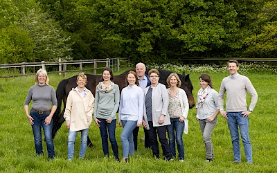 Das Team posiert mit einem Pferd auf der Weide