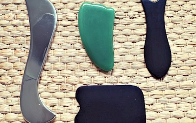 Vier verschiedene Gua Sha Schaber auf einer Matte